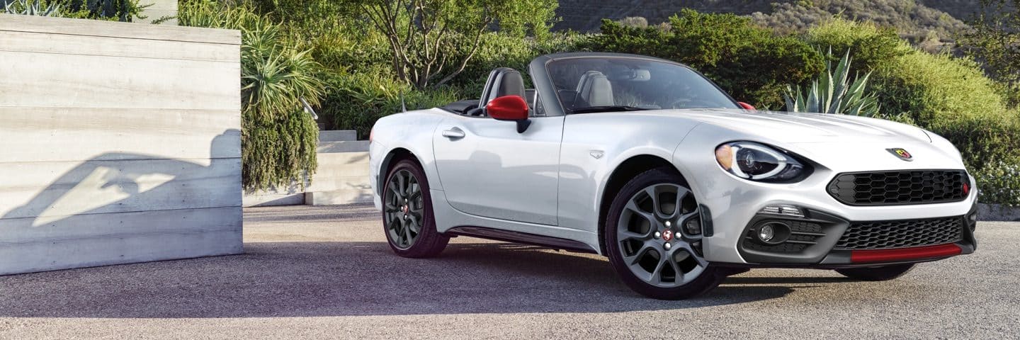 A white 2020 Fiat 124 Spider Abarth parked, with the top down.