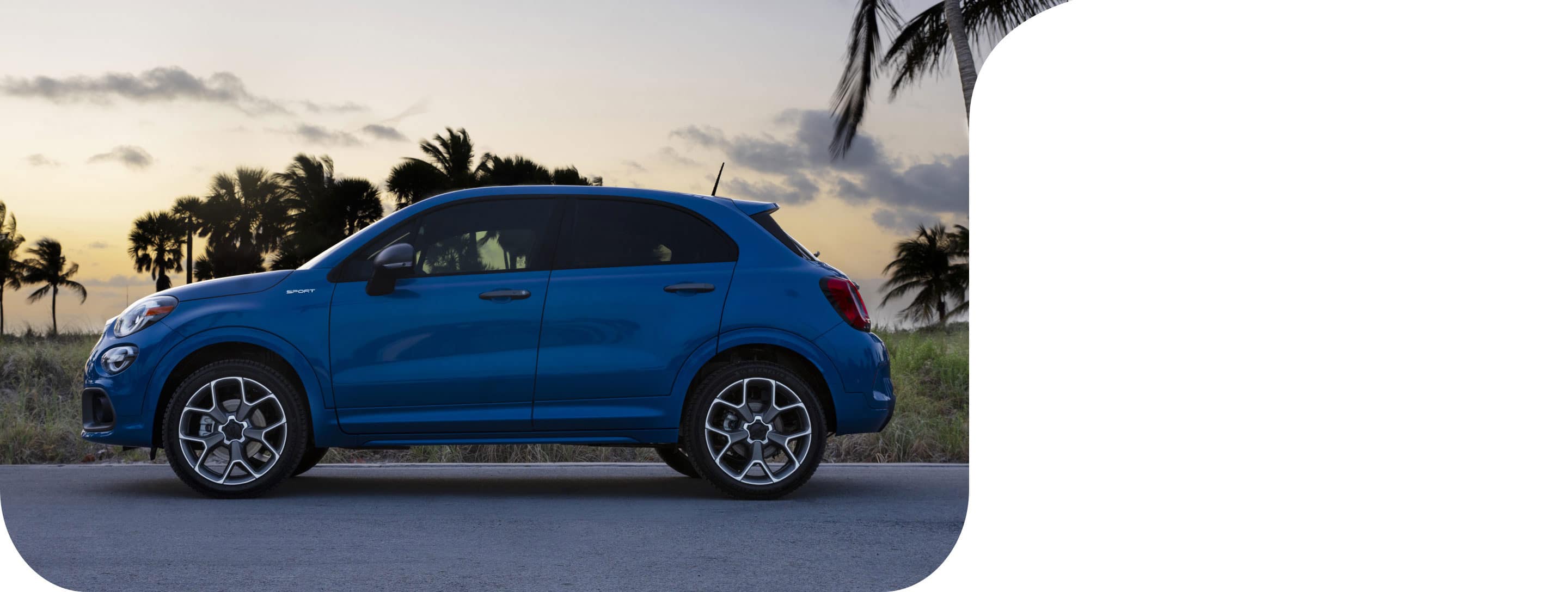 A profile view of a blue 2021 Fiat 500X Sport parked with palm trees in the background.