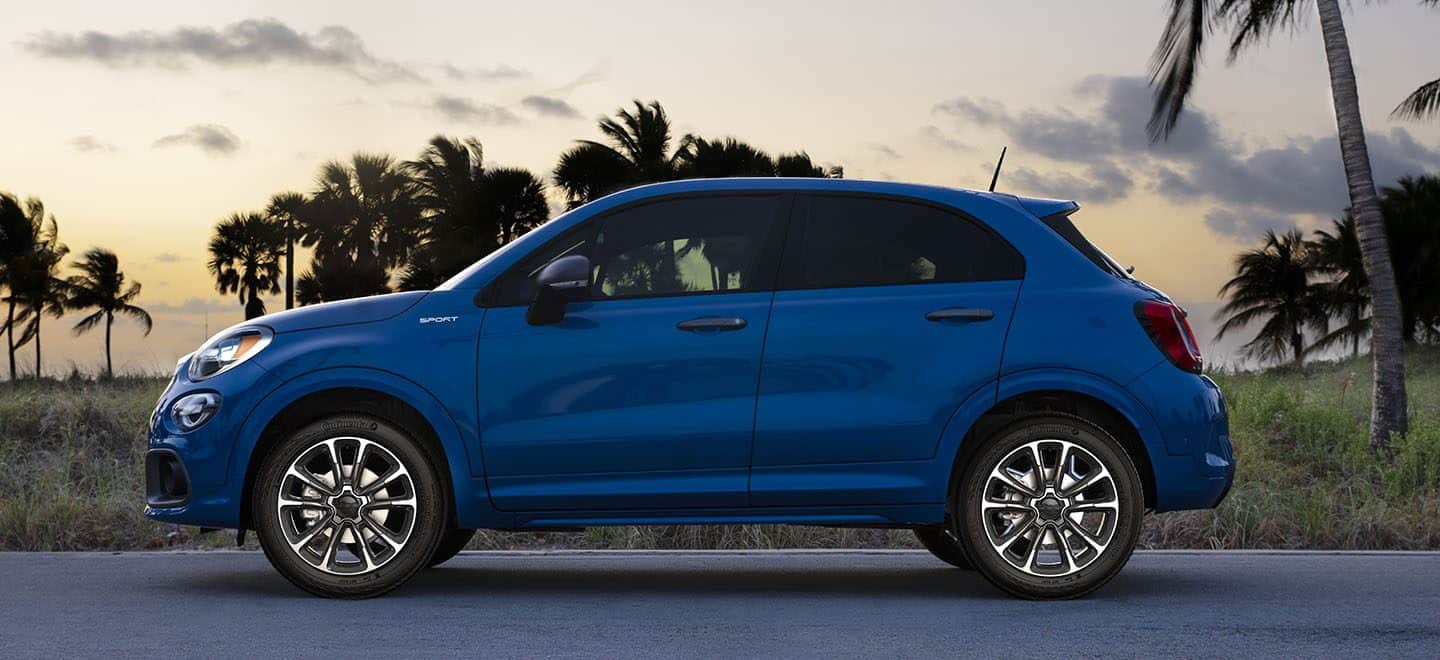 Display A profile view of a blue 2021 Fiat 500X Sport parked with palm trees in the background.