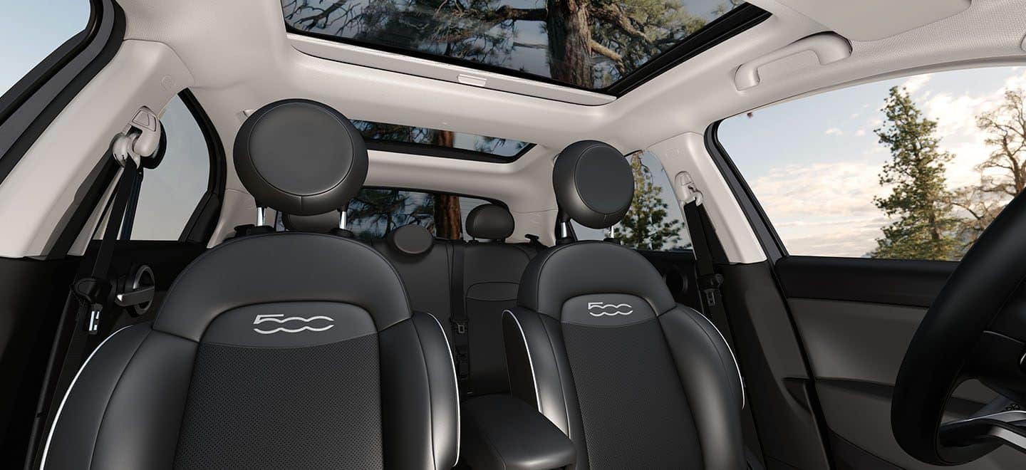 Display The interior of a 2021 Fiat 500X Trekking focusing on the front seats and open sunroof.