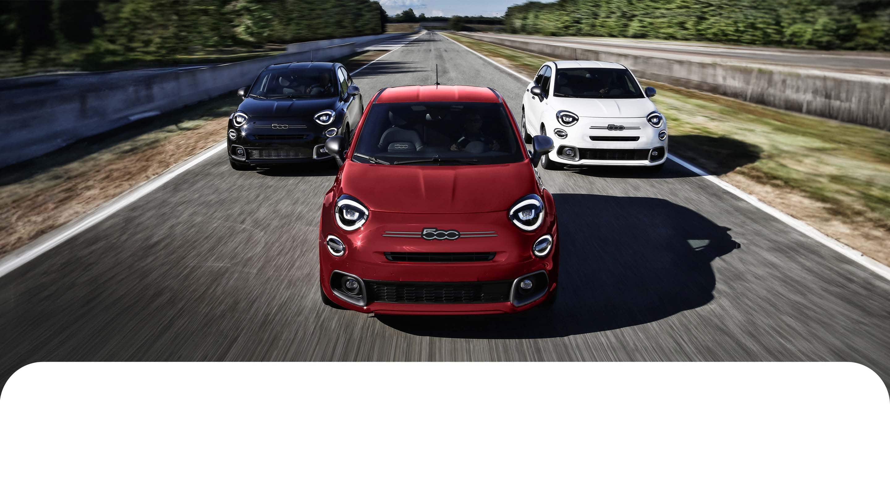 A head-on angle of three 2023 Fiat 500X Sport models being driven on a track. From left to right: One blue, one red and one white.