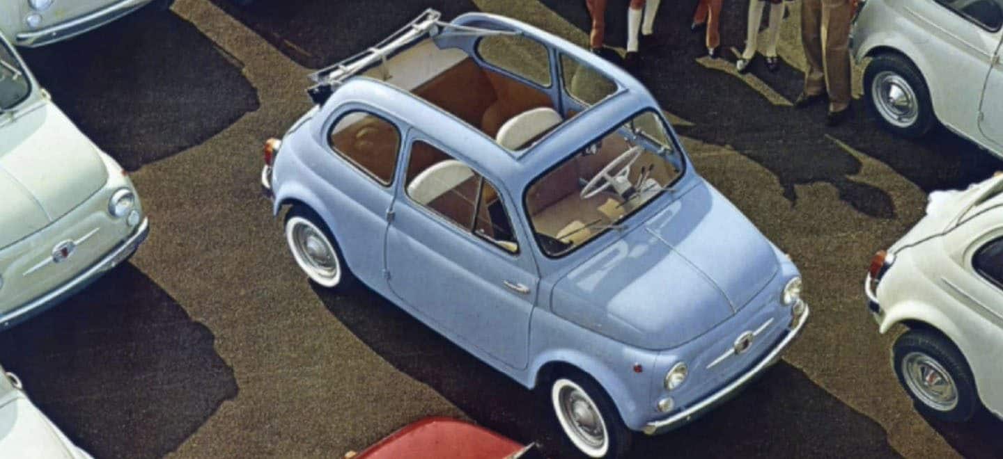 Display A vintage drawing from above of a classic sky blue Fiat Cabrio parked among several other classic Fiat vehicles.