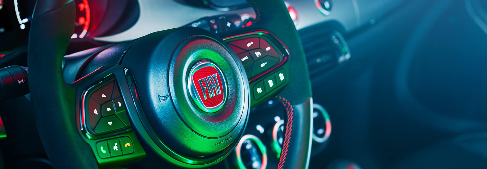 A close-up of the steering wheel on the 2022 Fiat 500X Sport, highlighted in a hue of neon green.