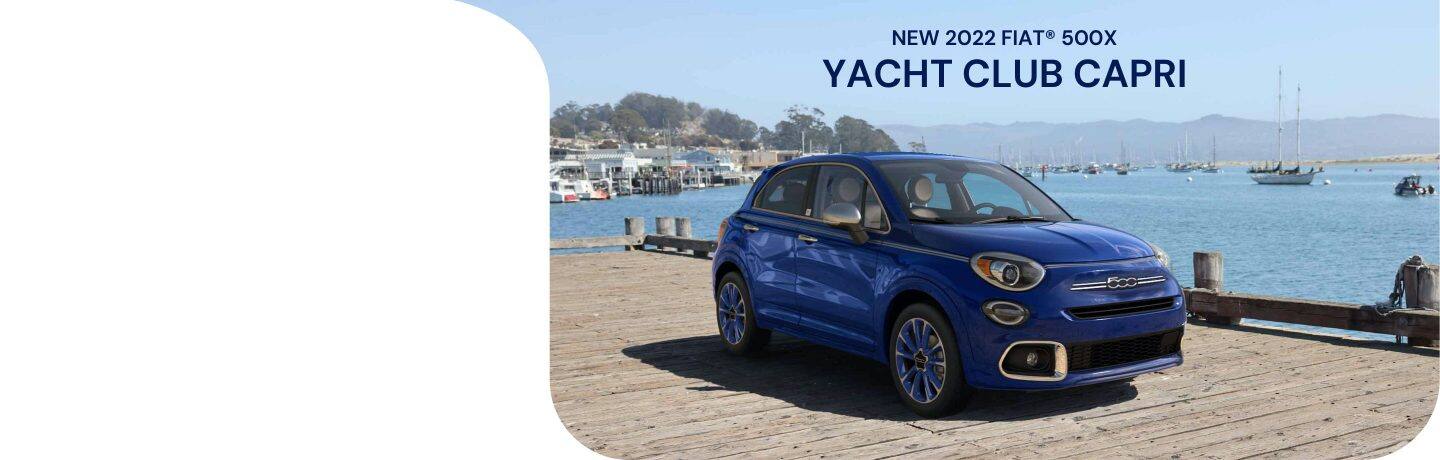 A blue 2022 Fiat 500X Yacht Club Capri, parked on a pier at the water's edge.
