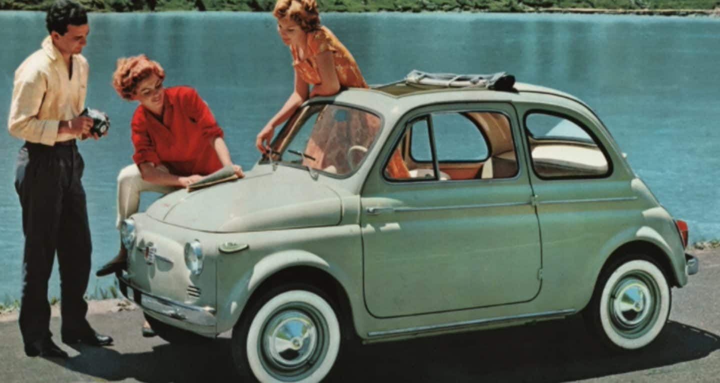Fondo de pantalla n.° 6: un dibujo vintage de un Fiat 500 Cabrio verde claro clásico estacionado junto a un cuerpo de agua con dos mujeres y un hombre parados cerca.