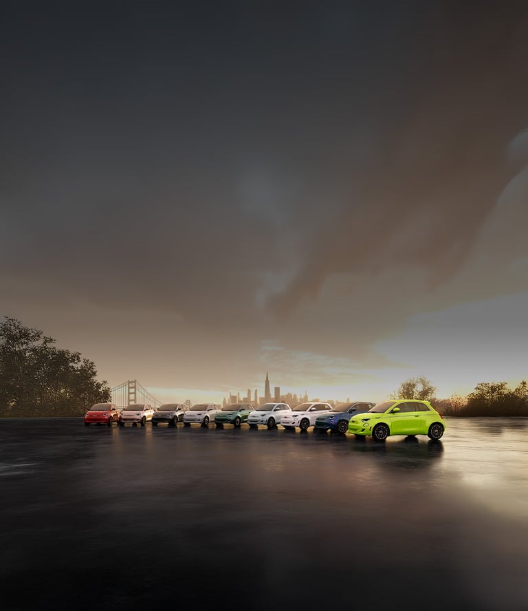 A combination of nine 2025 Fiat 500e Inspired, Icona and Giorgio Armani Collector's Edition models, parked side-by-side with a suspension bridge and cityscape in the background. Vehicle exterior colors include red, rose gold, black, white, green, blue and tennis ball yellow-green.