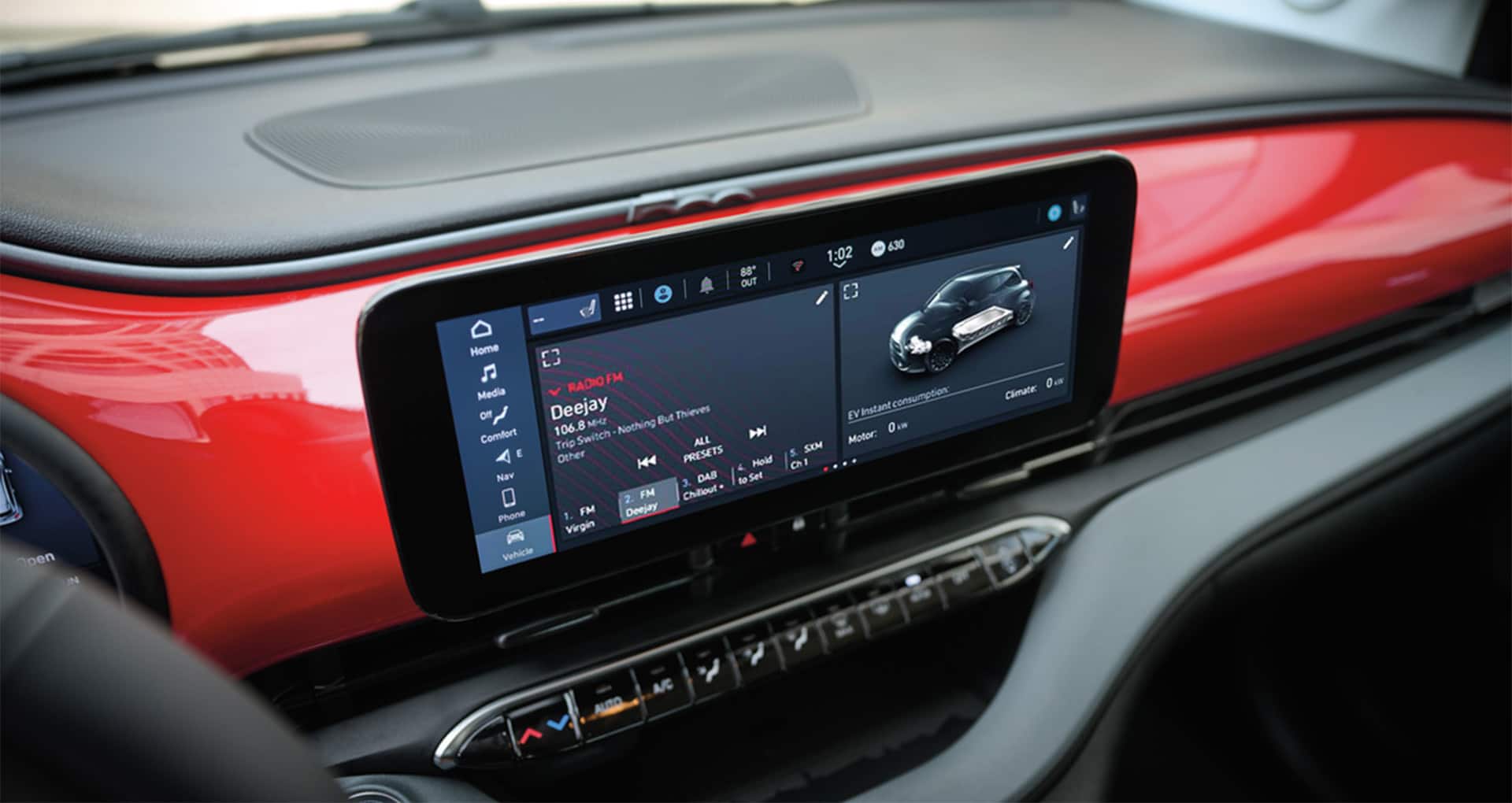 The Uconnect touchscreen in the 2025 Fiat 500e Red, with a split screen displaying an FM radio selection and EV instant consumption.