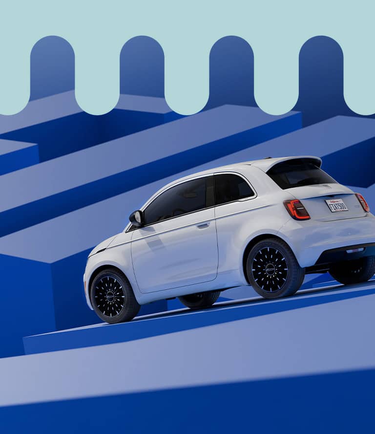 A white 2026 Fiat 500e Icona shot from a lowered driver-side rear angle.