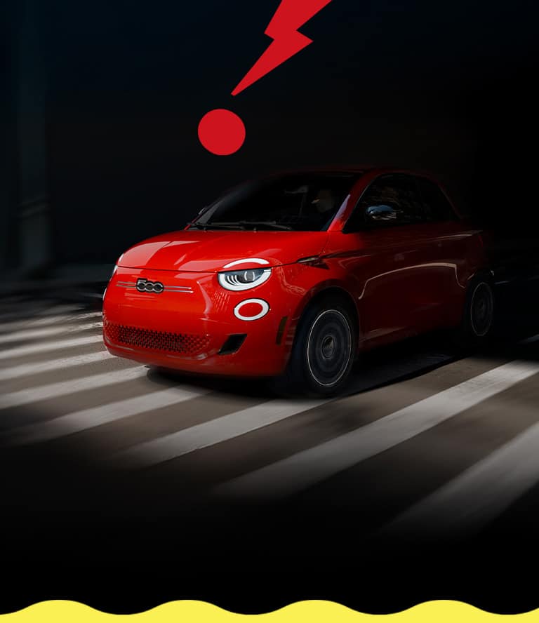 A driver-side front angle of a red 2025 Fiat 500e Inspired emerging from the dark into the light, on a striped track with a large red zigzagged exclamation point in the background.