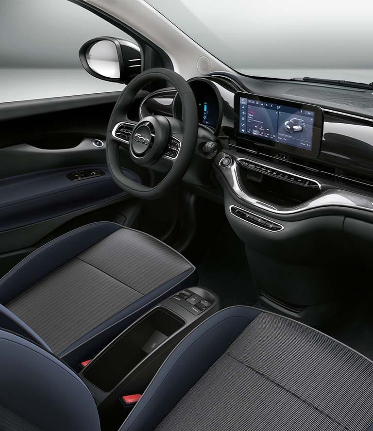 The interior of the 2024 Fiat 500e La Prima, focusing on the steering wheel, Uconnect touchscreen and dash.