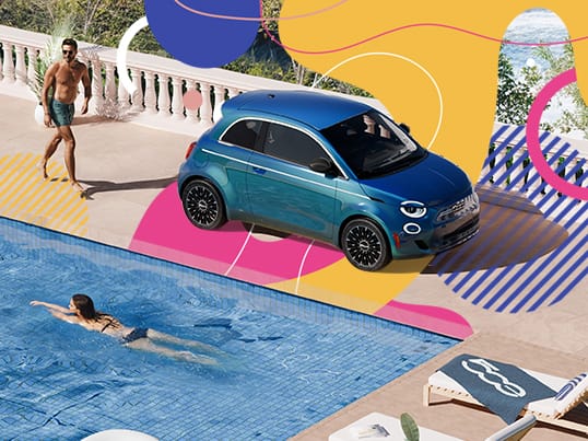 A Fiat 500e sits parked by the pool at a resort.