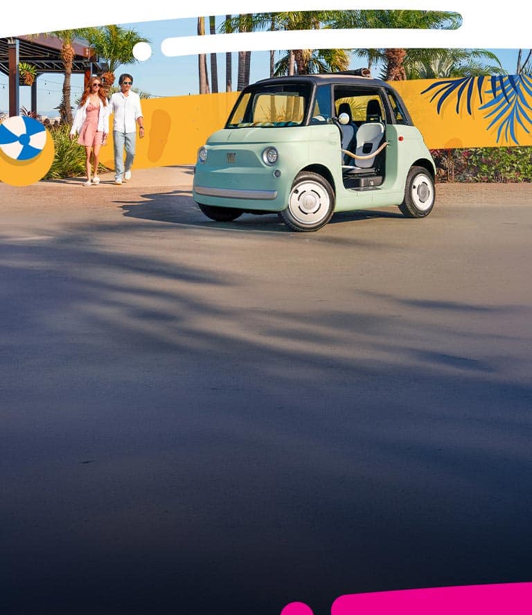 A passenger-side profile of a light green Fiat Topolino parked in front of a tennis club, with a couple exiting the club.