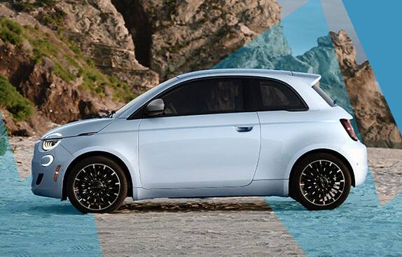 A driver-side profile of a marine blue 2024 Fiat 500e Inspired By Los Angeles parked on a beach with sea stacks in the background and animated blue lightening bolts in front of and behind the vehicle.